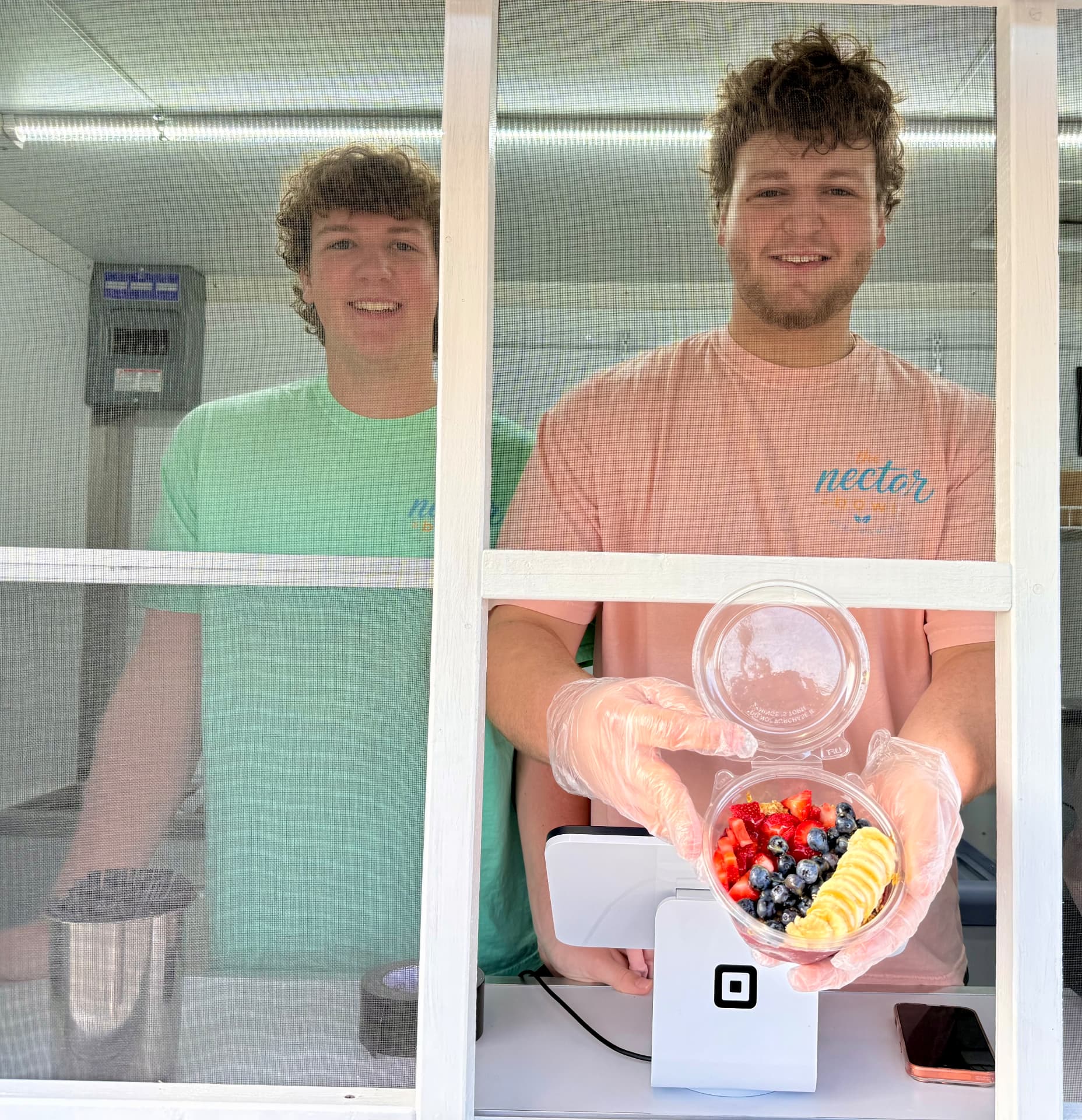 Two brothers serving a fresh açaí bowl from the trailer window